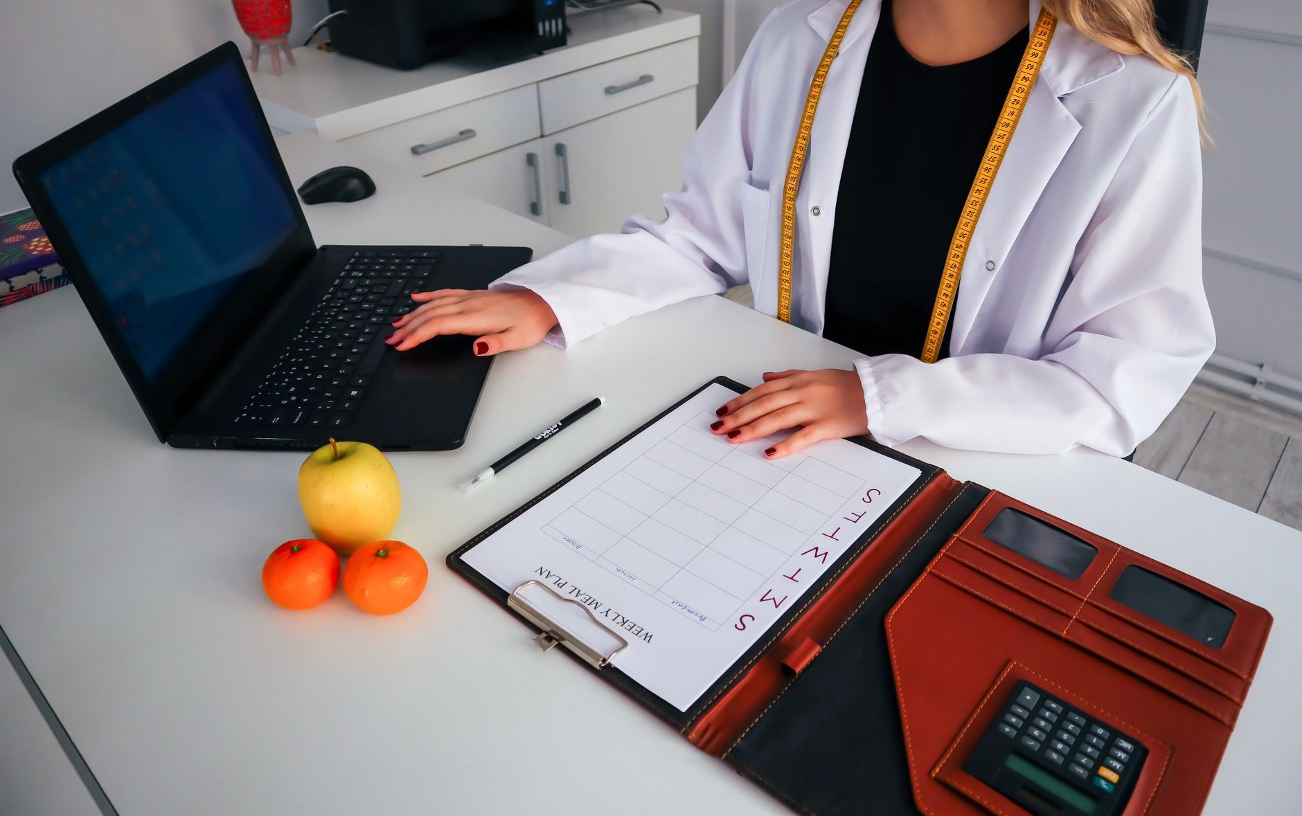 A nutrition worker plans meals at a table with food notes and reference materials